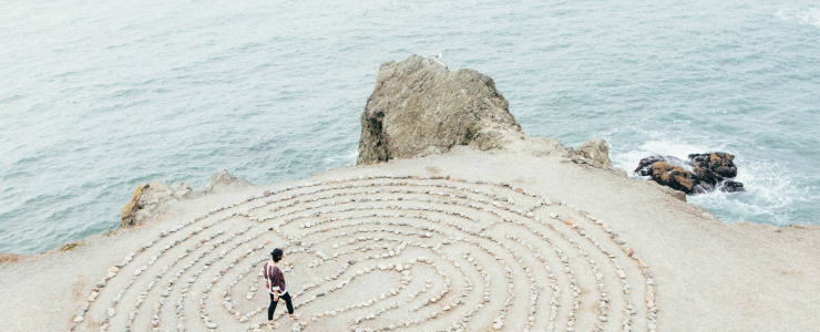 A person walks a labyrinth on a sandy beach
